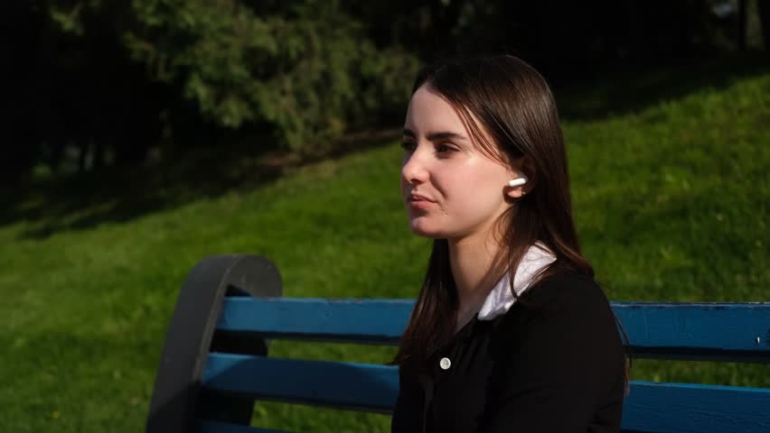 portrait of a young beautiful woman listening to music on wireless headphones in nature