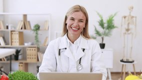 Mature nutritionist doctor with fruits in office. Nutritionist working on laptop and writing diet plan for patient. Portrait of female nutritionist in office. Smiling young dietician sitting at desk. - Powered by Shutterstock - Get 15% off with code: PIKWIZARD15