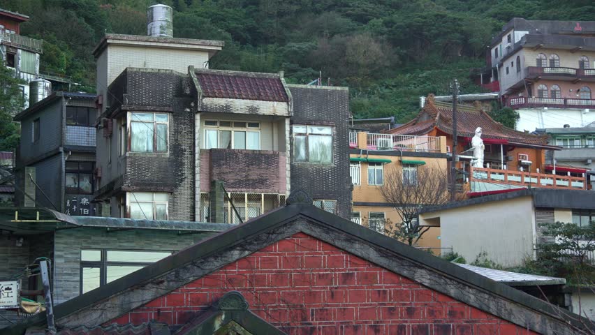 Panning view capturing traditional houses perched on mountainside at Jiufen Old Street, quaint mountain village town in Ruifang district, New Taipei City, Taiwan.