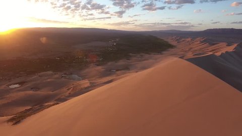Aerial drone shot over windy sand dunes during sunrise in Gobi desert southern Mongolia. Shot in 4K (UHD). Beautiful oasis with river. Shot with DJI Phantom4