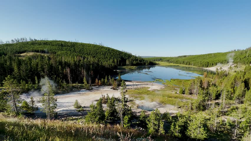 Yellowstone Park with rushing geysers, multicolored hot springs, crystal clear lakes and impressive canyons. Bears and bison. Wyoming, Idaho and Montana. Yellostone natural spectacle. Sunset.