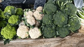 At a market stall there are various organic vegetables on display, including broccoli and cauliflower. The vegetables are fresh and colourful, and are arranged in an appetising way. - Powered by Shutterstock - Get 15% off with code: PIKWIZARD15