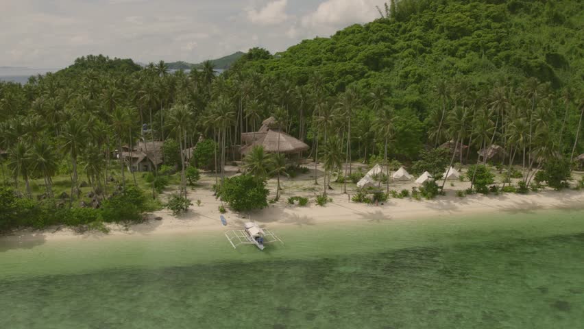 Aerial view of secluded eco resort surrounded by turquoise ocean, lush forest, and palm trees, Daracoton Island, Philippines.