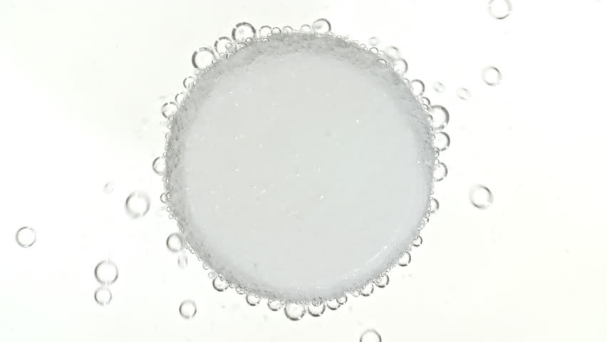 Close-up Effervescent tablet aspirin, vitamins on a white background. Macro shot of fine air bubbles in water in a petri dish. The medicine concept, health care, treatment. Slow motion.