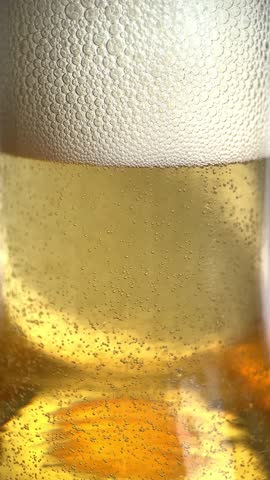 Close-up of a bottle of fresh cold beer covered with drops, bubbles rise, a drop runs down the beer bottle