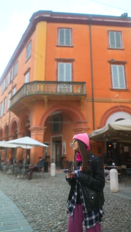 A pretty girl wanders through an Italian city with an audio guide playing in her earbuds.