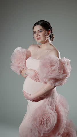 Young pregnant woman gently caresses her belly in anticipation of baby.