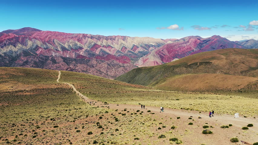 Drone advances over a path as tourists journey towards the Mirador del Cerro de los 14 Colores, also known as Hornocal.