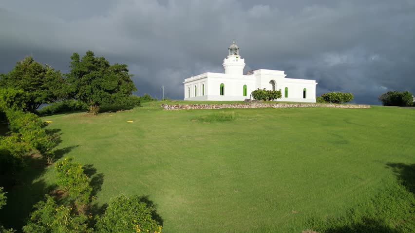 fajardo lighthouse (faro las cabezas de san juan) on a tropical rainforest jungle hilltop in caribbean sea (flying drone footage from above) puerto rico coast coastline seascape