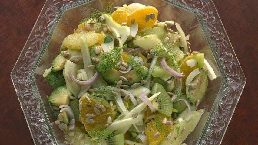 Fennel salad with citrus and avocado in a cristal glass bowl. Table spin. Zoom in while rotating.