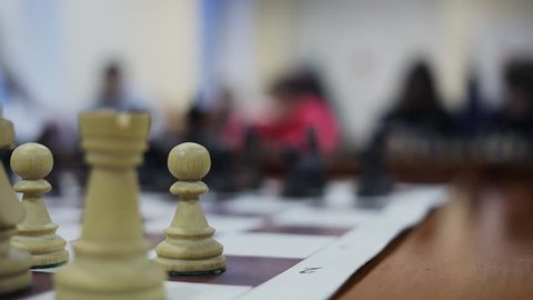 Five people play chess against one man on different chessboards on tables, focus changes