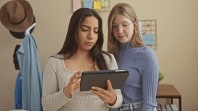 Two women friends smile and use tablet in modern living room - Powered by Shutterstock - Get 15% off with code: PIKWIZARD15