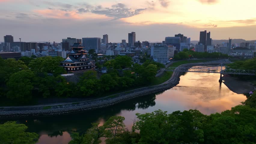 Japanese traditional castle in Okayama in the evening with city lights and sunset, aerial shot of samurai castle in Japan at night . High quality 4k footage