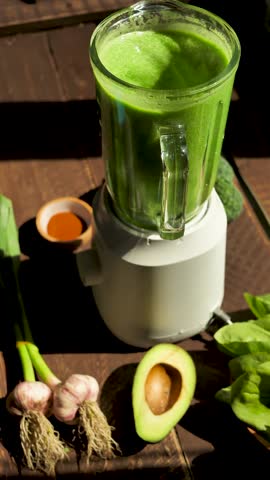 Vertical screen: blending green vegetable and herbal smoothie in a blender for drinking. Slow rotation of a green vegetarian smoothie in a blender. A healthy and nutritious drink for vegans. Diet