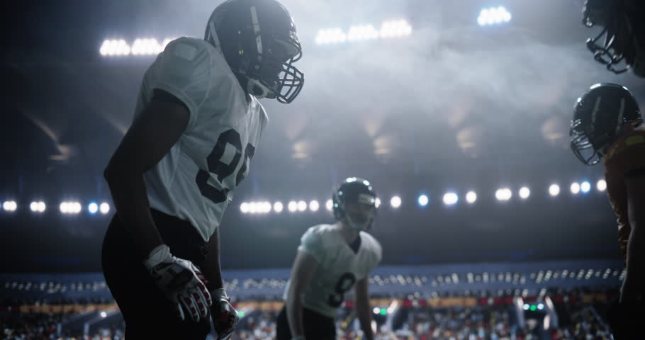 Cinematic Footage of an American Football Match with Players Standoff Before Action, Tackles, and Strategic Plays Begin. Professional Male Footballers Fighting for the Ball, Playing a Dominant Game