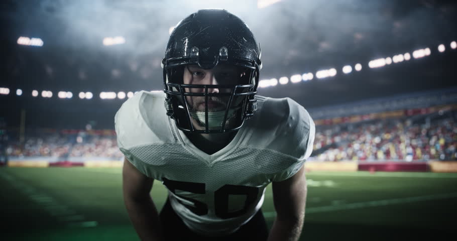 Focused Caucasian Male American Football Player in a Helmet and Protective Uniform. Close Up Portrait of a Footballer on a Stadium Field, Standing in a Position for a Championship Game to Begin