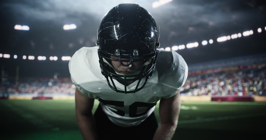 American Football Player Standing in a Stadium Under Heavy Rain, Looking at Camera. Footballer Standing in a Position for a Standoff with Opponent Team, Motivated to Play a Competitive Match