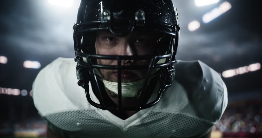 American Football Player Standing in a Stadium Under Heavy Rain, Looking at Camera. Footballer Standing in a Position for a Standoff with Opponent Team, Motivated to Play a Competitive Match