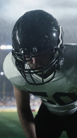 Vertical Screen: Serious, Angry, Determined American Football Player Preparing for a Game. Footballer Standing in the Arena in Heavy Rain, Breathing Heavily, Motivated to Win the Championship