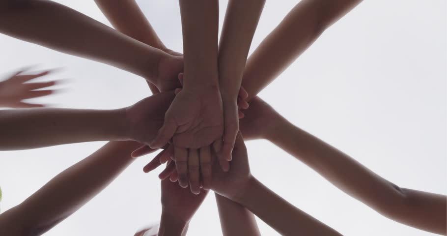 Successful team, many hands holding together on sky background
