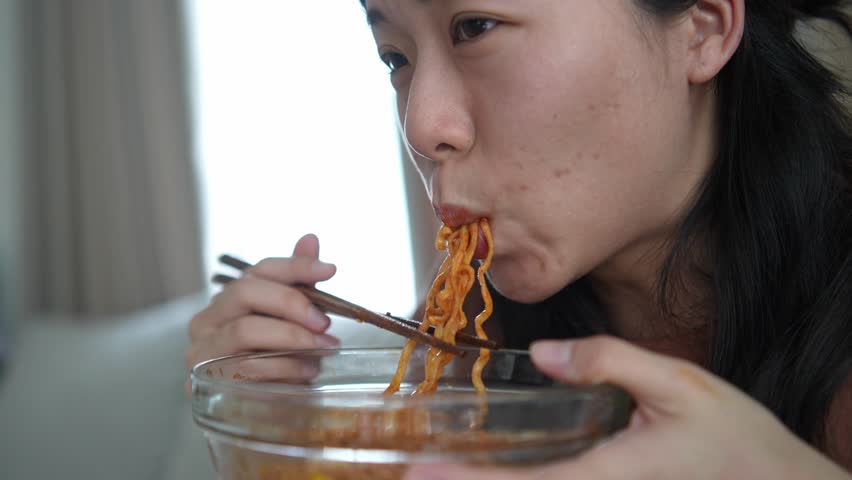Close up expression face of woman eating spicy ramen noodles
