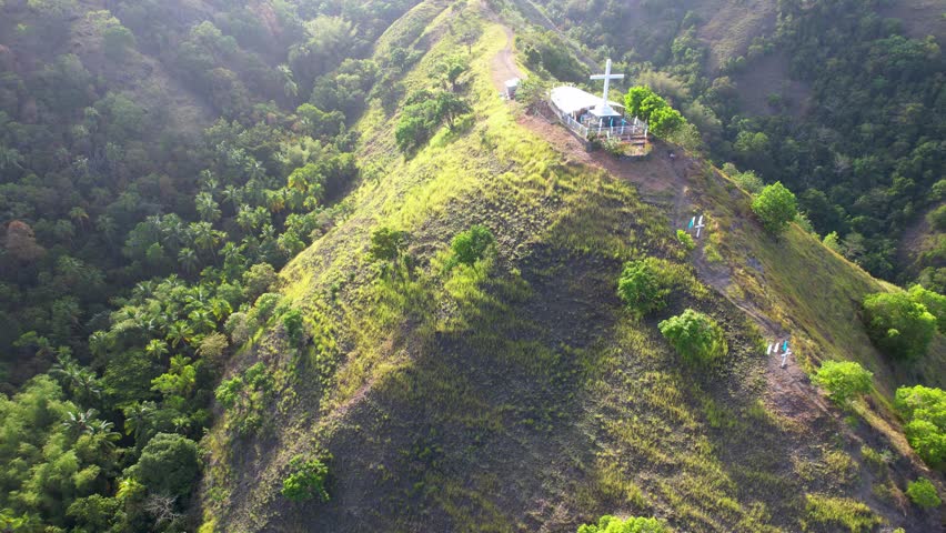 4K Aerial Drone video of beautiful mountain range with tracks and crosses and the christian chapel on the top, on a sunny day with the view on the sea coastline, Holy Mountain, Siquijor, Philippines