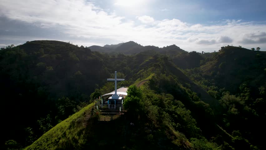 4K Aerial Drone video of beautiful mountain range with tracks and crosses and the christian chapel on the top, on a sunny day with the view on the sea coastline, Holy Mountain, Siquijor, Philippines