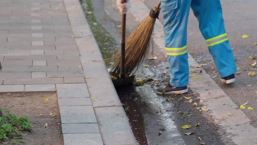 Road sweeper worker cleaning city street with broom tool in Hanoi, Vietnam