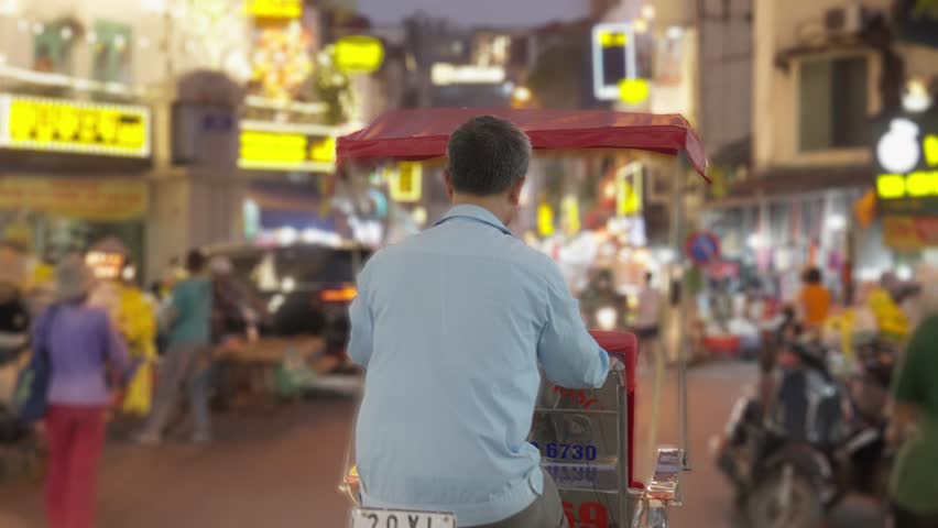 Cyclo (pedicab) driver on Hanoi old town at dusk