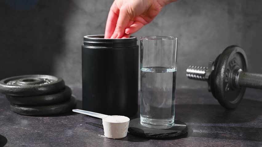 Amino acid food supplement, creatine powder in a measuring scoop and plastic jar