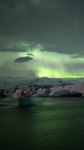 Aurora borealis over mushroom shaped iceberg Jokulsarlon Iceland vertical