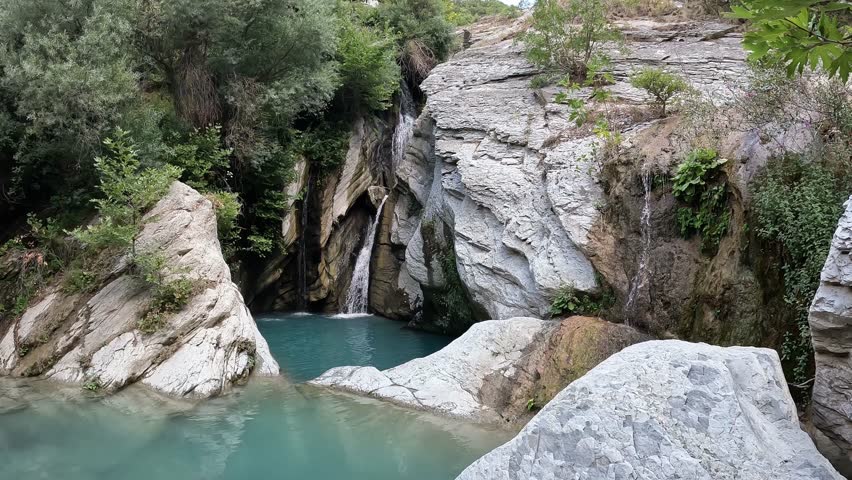 Shot of the waterfall near Bogova Albania on a sunny day with no people and clear water with rocks and plants around LOG, Albania bogova waterfall
