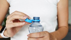 Bottle with stationary plastic cap in woman hand. The new design means the cap remains attached to the bottle after opening, making the entire package easier to collect and recycle. 4k footage - Powered by Shutterstock - Get 15% off with code: PIKWIZARD15