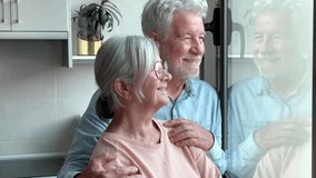 A happy senior retired couple hugging near the window enjoying a quiet moment together at home. Handsome elderly man and woman looking into each other's eyes with love - Powered by Shutterstock - Get 15% off with code: PIKWIZARD15