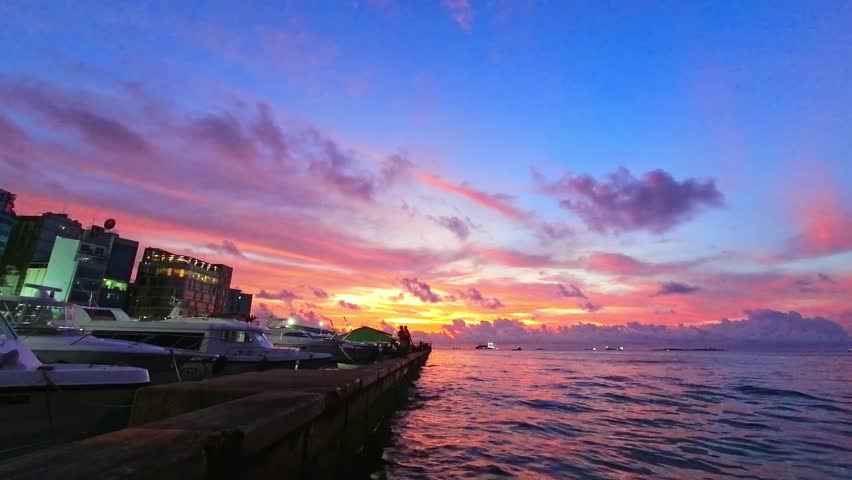 Boats and yachts in harbor time lapse on sunset in Male capital harbor, Maldives. Purple dramatic sunset panoramic view