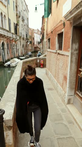 Venice, Italy. A tourist girl strolls through the city streets, snapping photos with her smartphone.