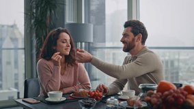 Enamoured man feeding wife with strawberry at kitchen closeup. Cute flirting lovers enjoying breakfast spending time together at big windows flat. Happy couple eating berries talking at panoramic home - Powered by Shutterstock - Get 15% off with code: PIKWIZARD15