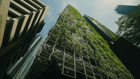 Low view of a modern skyscraper featuring a vertical garden facade. The building integrates greenery into its architecture, in an urban environment and showcasing innovative design. Zoom in - Powered by Shutterstock - Get 15% off with code: PIKWIZARD15