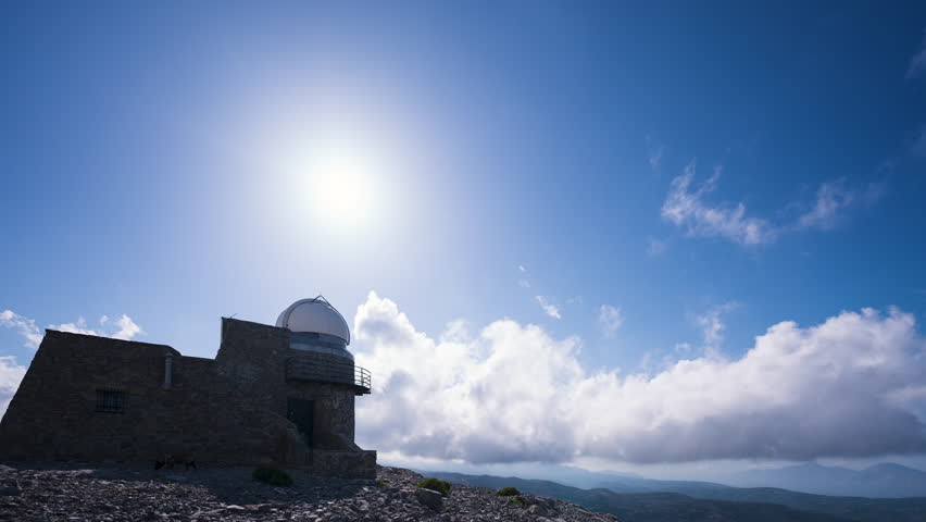 Sunset high in the mountains over an astronomical observatory, powerful clouds dragged by the wind