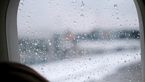 View of raindrops flowing down an airplane window close-up. Rainy weather. Passengers await departure in the aircraft cabin. Departure delayed due to bad weather conditions and poor visibility. 4K. - Powered by Shutterstock - Get 15% off with code: PIKWIZARD15