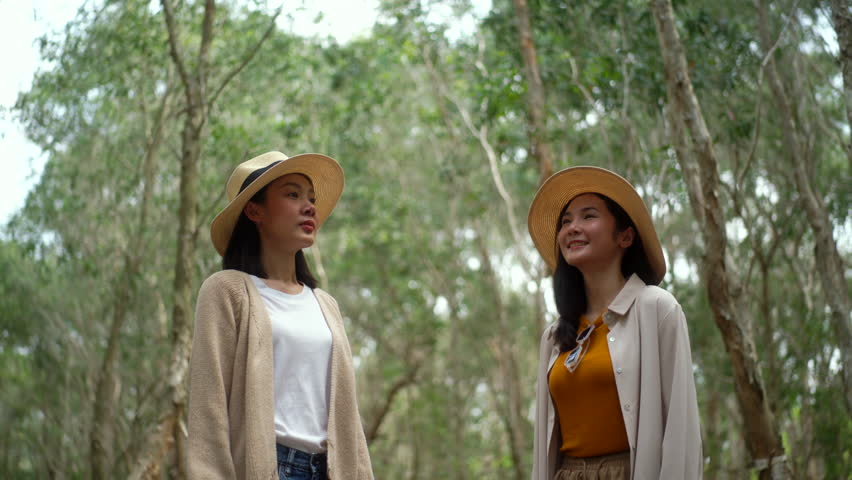 Happy two asian women traveling botanic natural forest while while taking deep breath fresh air, young joyful female relaxing on vacation, concept of people enjoy outdoor lifestyle  
