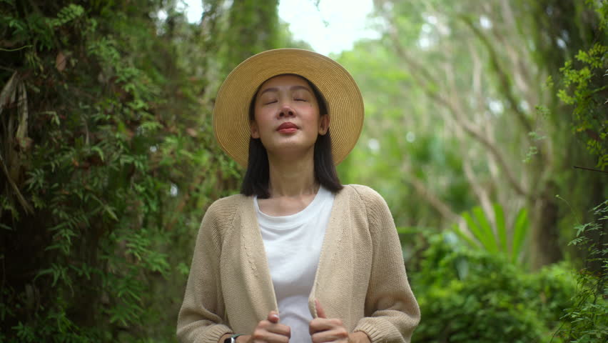 Happy asian young woman traveling and taking deep breath in botanic natural forest, young joyful female relaxing on vacation, concept of people enjoy outdoor lifestyle in summer 
