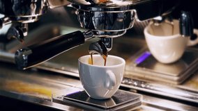 Close-up of the Espresso coffee extraction from a professional coffee machine with a bottomless filter. Coffee flowing into cup. Coffee aroma and the warm shop atmosphere - Powered by Shutterstock - Get 15% off with code: PIKWIZARD15