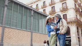 Front view of senior married couple walking and talking in the city, smiling at camera. Happy older tourist sightseeing old town on vacation. - Powered by Shutterstock - Get 15% off with code: PIKWIZARD15
