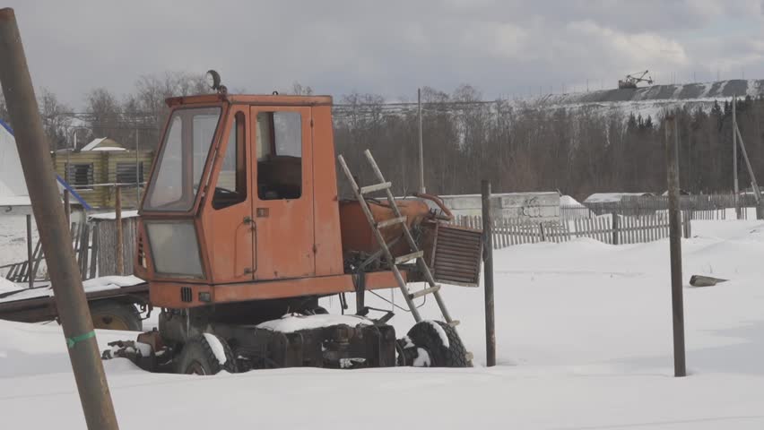 Vehicle parked in snow next to wooden fence on freezing slope