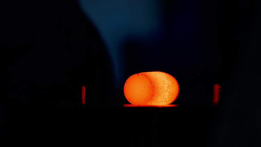 Manufacturing process of metal parts from Cylindrical billets. Metal forging, forging shop. Hydraulic hammer shapes the red-hot billet. Production of high-tech parts. Super slow motion video