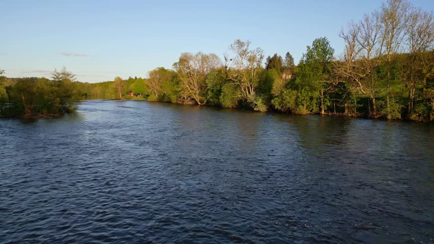 Drone flying at low altitude over Vienne river in Saint-Victurnien countryside, Nouvelle-Aquitaine in France. Aerial backward