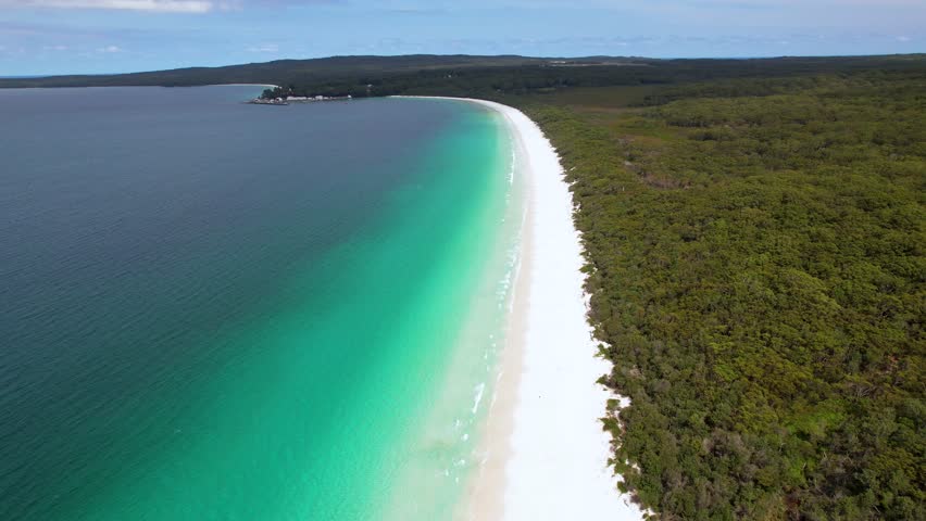 A 4K drone view of Hyams Beach, a stunning white sand beach in Jervis Bay, New South Wales. This white sand beach has lush green rainforest on one side and a blue ocean on the other. Australia.
