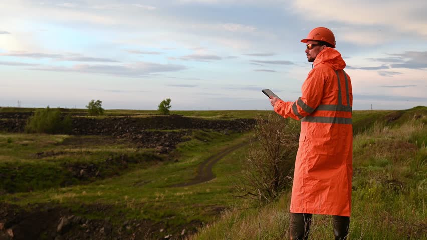 a man in a raincoat and a protective helmet with a tablet