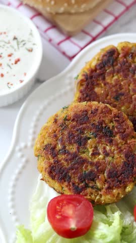 Vegan meat for burgers with lettuce and cherry tomatoes. Chickpea plant-based patties with vegetables, herbs and spices. Vertical video. Top view.